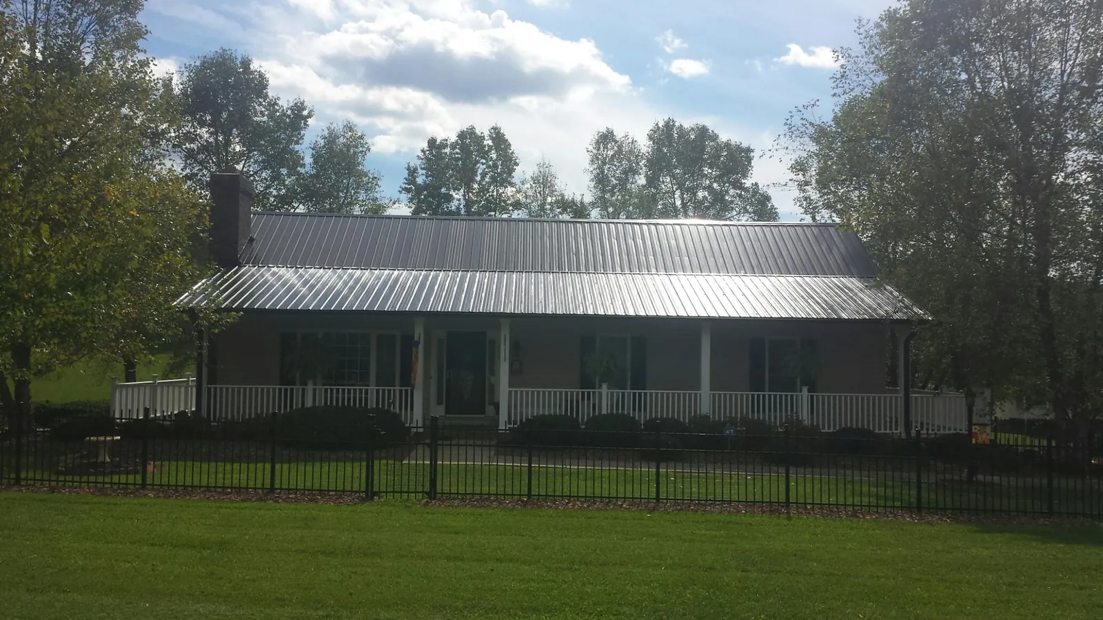 Gray metal roof on a brick ranch with a full width front porch — Gutter Guard Installation work by our crew in Williamsport